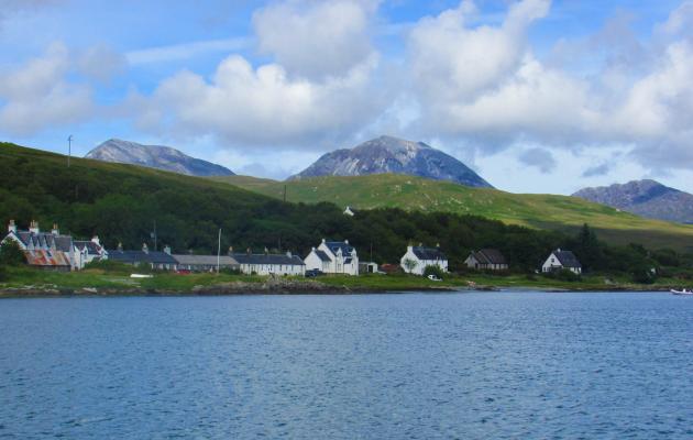 Image of the Paps of Jura and some houses in front next to the sea.