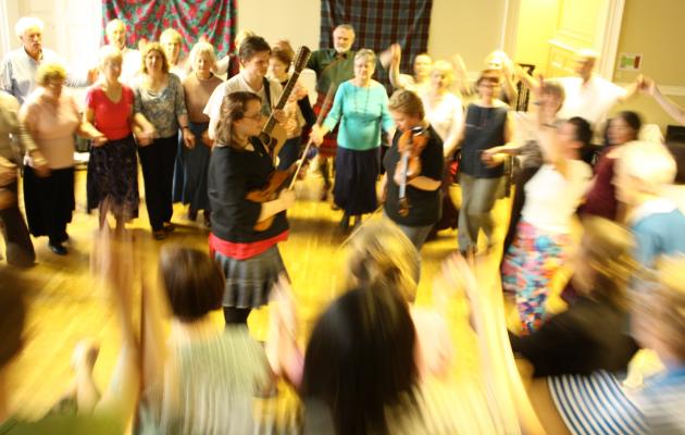 Image of people dancing in a community space at a ceilidh