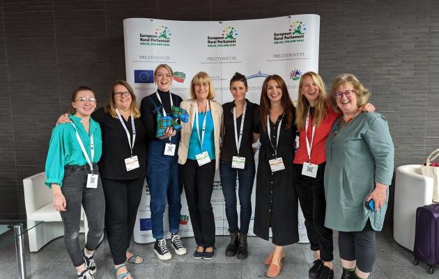 Image of the Scottish Delegations (8 people) standing in front of the European Rural Parliament poster