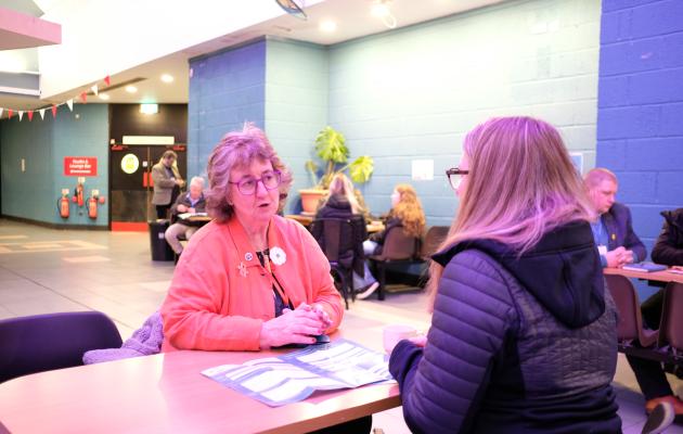 Two delegates at a table talking in the Nevis Centre, Fort William