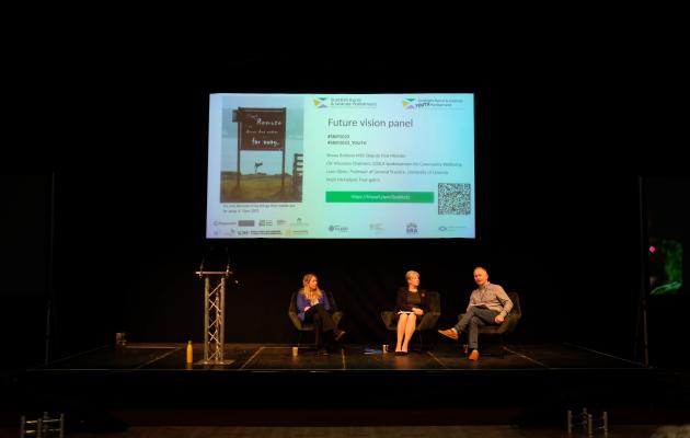 Image of people sitting down during a panel discussion with screen behind them