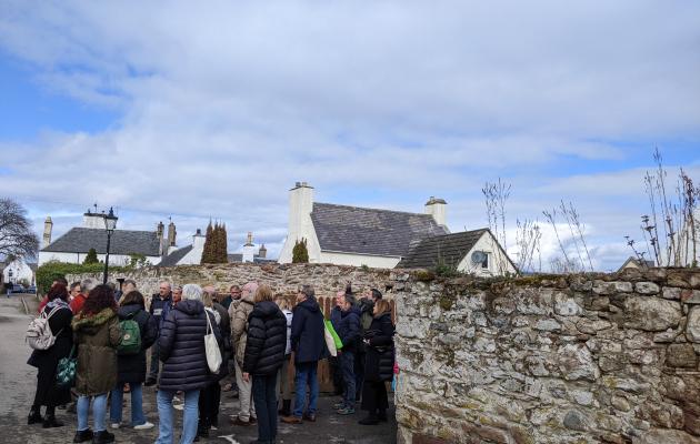 Image of people in a street next to a stone wall