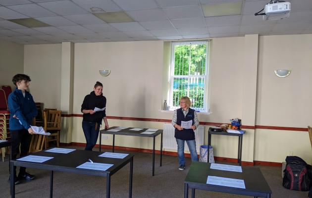 Image of Sheena and Artemis and Innes standing in a room holding paper