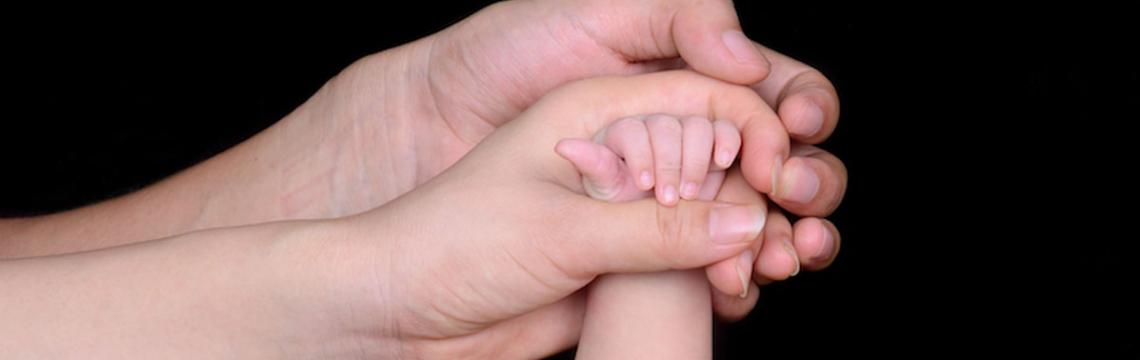 parent holds baby's hand