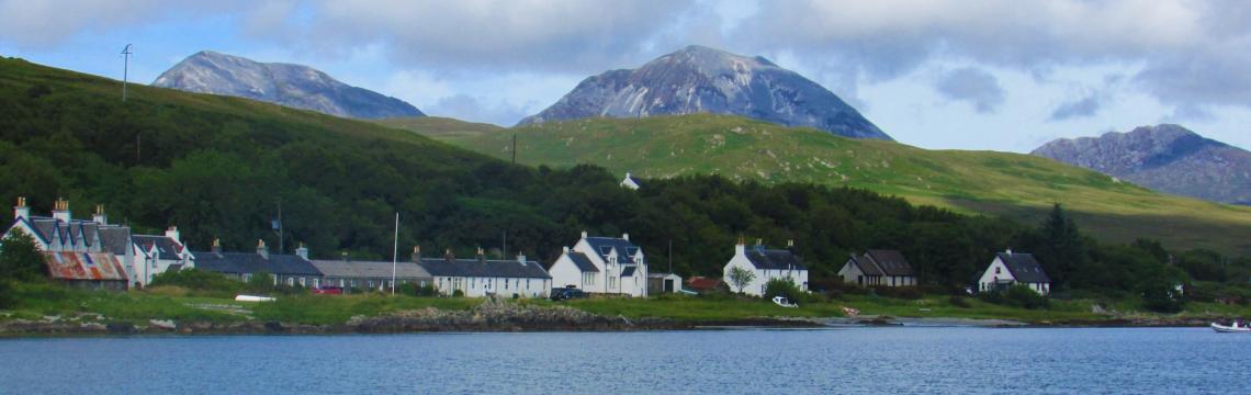 Image of the Paps of Jura and some houses in front next to the sea.