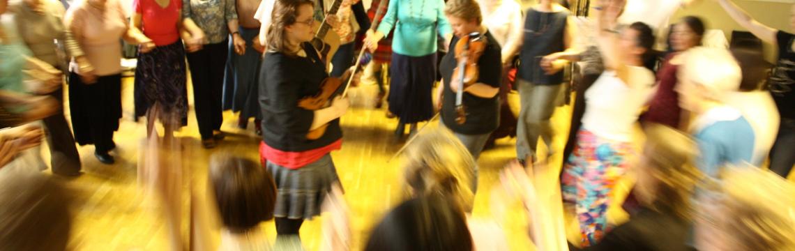 Image of people dancing in a community space at a ceilidh