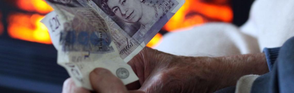 Image of someone holding money in front of fire