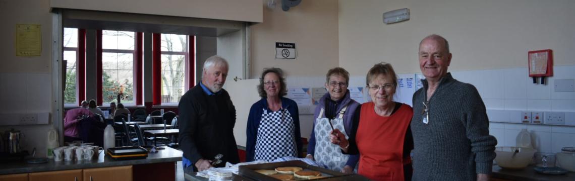 Image of people standing making pancakes